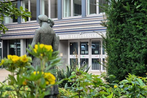 Foto Cuno Berufskolleg mit Statur und Blumen im Vordergrund